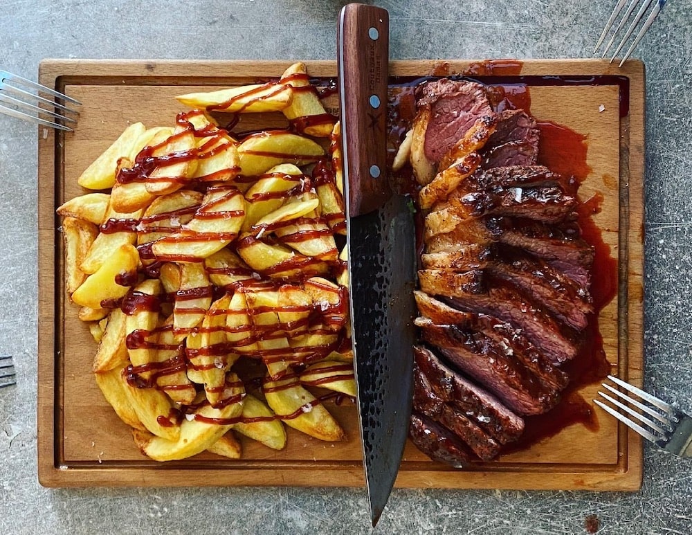 steak et quartiers de pommes de terre sur une planche à découper en bois